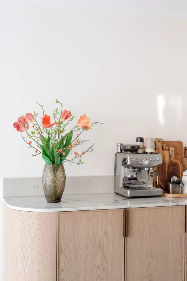 Kunst tulpenboeket oranje royaal in zalmoranje en koraal in een glazen vaas op een keukenblok