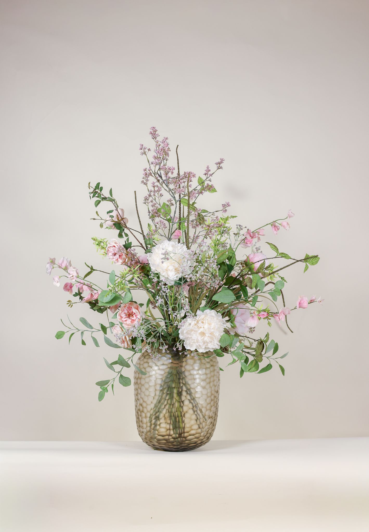 Zijden bloemstuk met roze rozen en witte pioenen in een glazen vaas