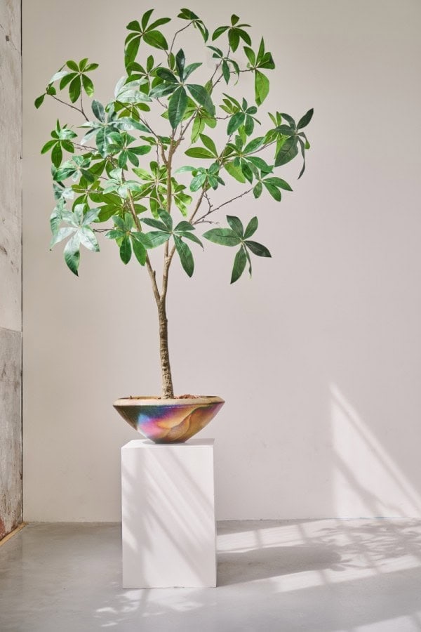 Luxe kunstboom in een pot op een witte sokkel