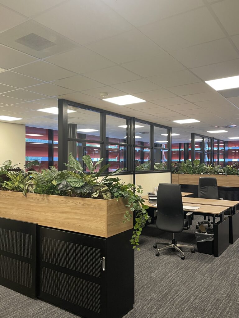 Zakelijke interieurbeplanting: plantenbakken met kunstplanten tussen de werkplekken van een kantoor