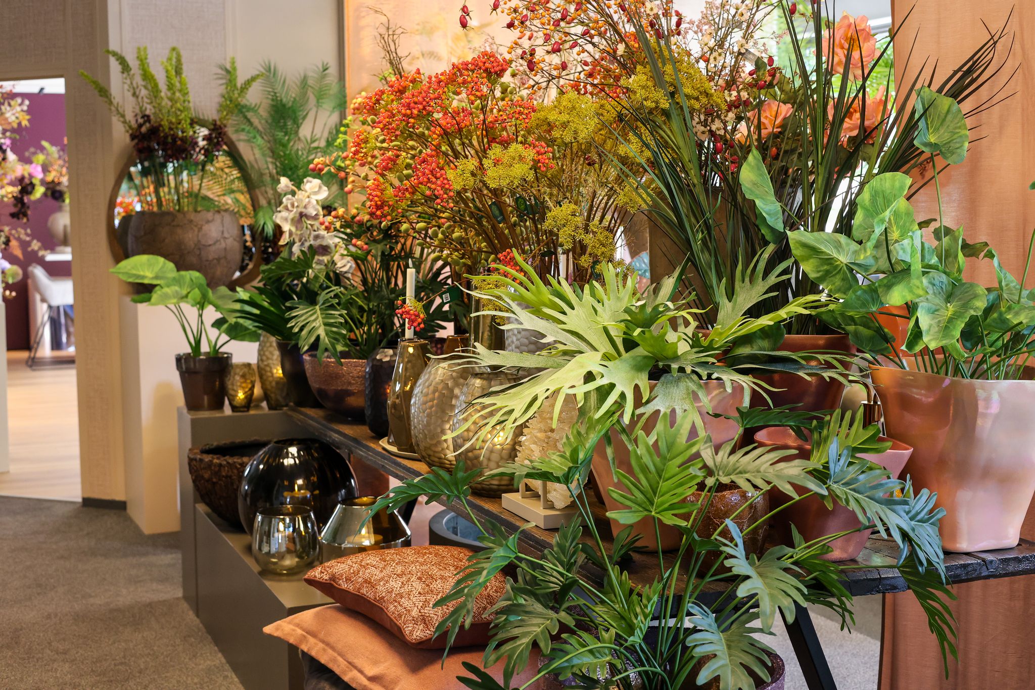 Luxe kunstbloemen, kunstplanten en glazen vazen op een houten tafel in de winkel van Exclusief Ingericht in Oss